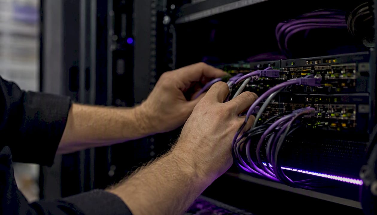 Hands configuring network cables in data center