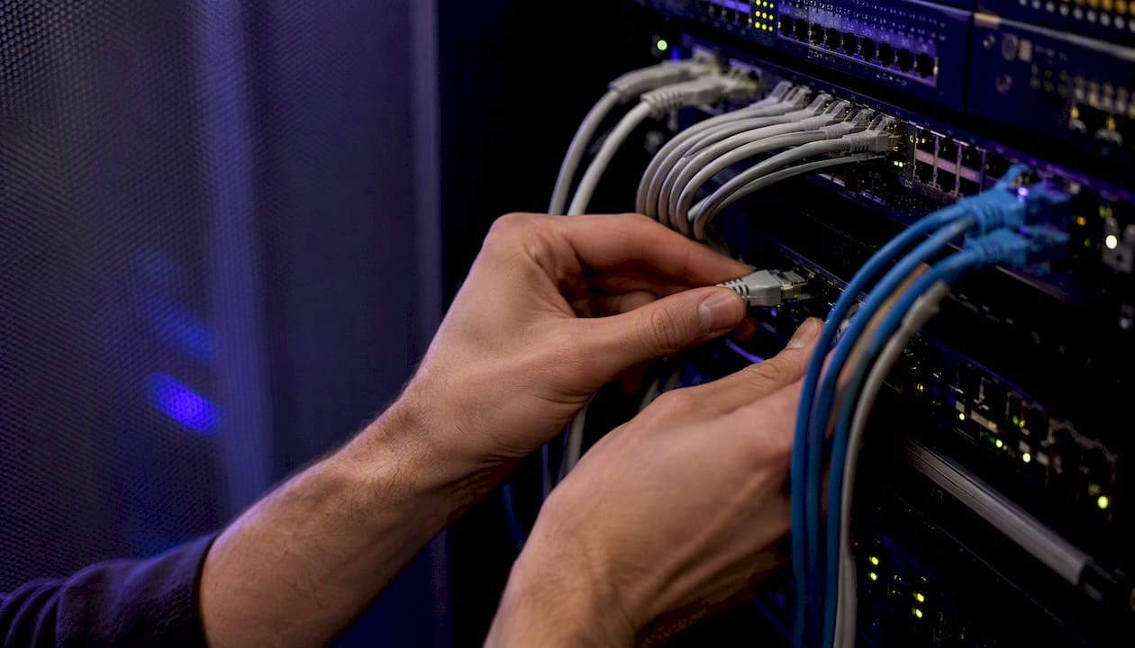 Hands adjusting cables in a server room