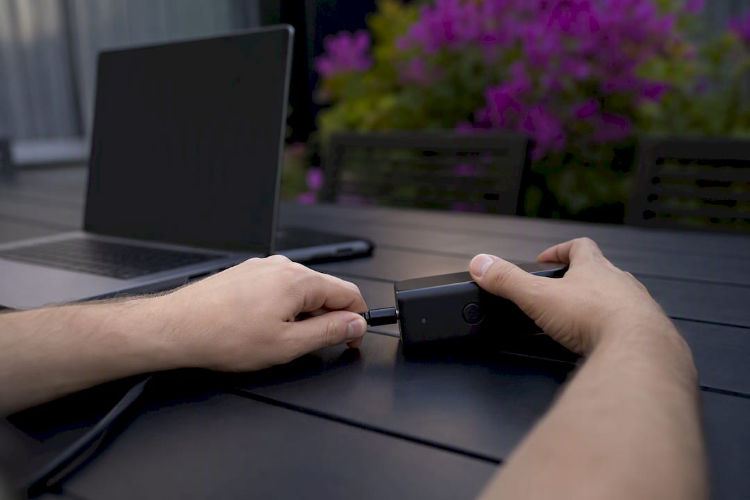 Hands connecting marketing devices on dark desk